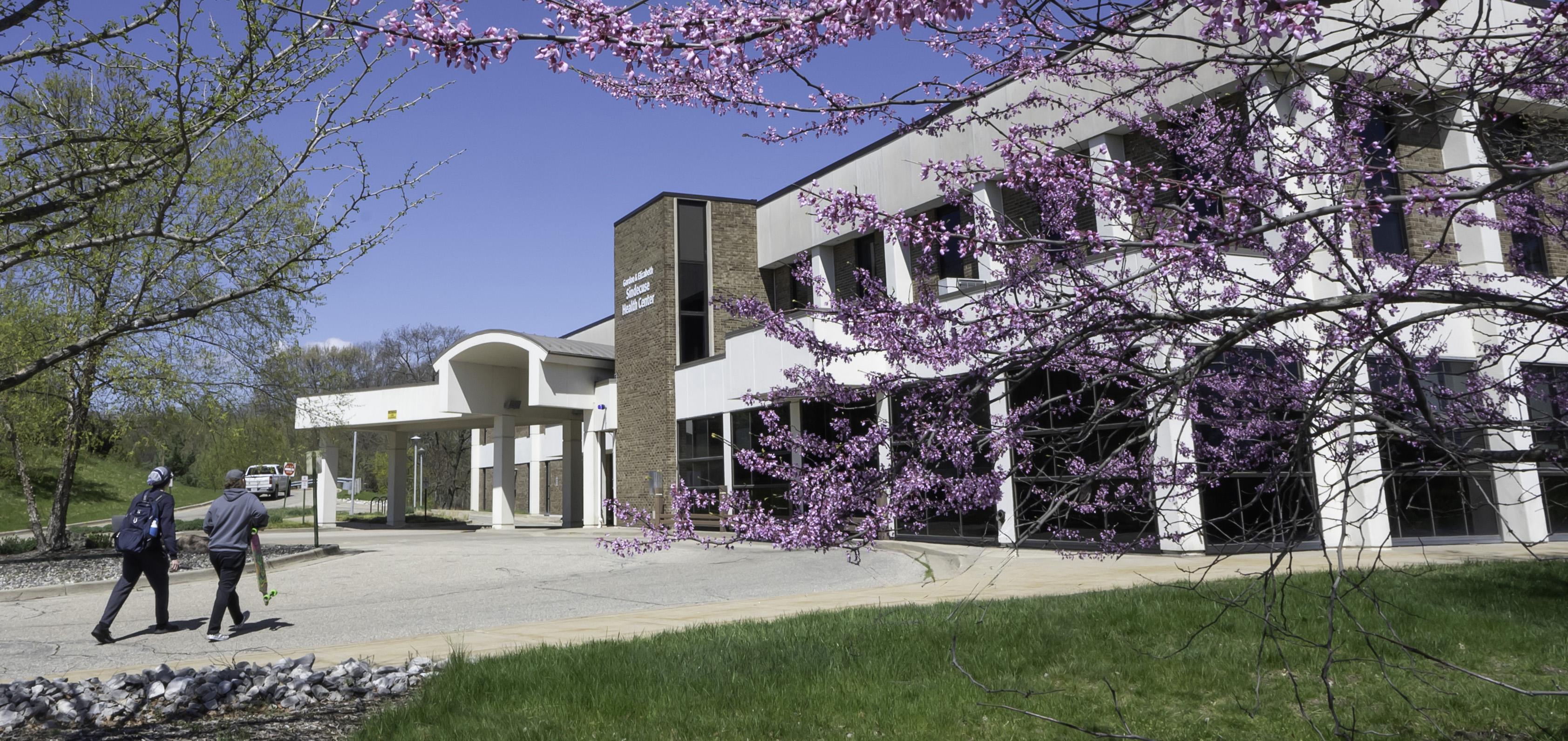 students walking toward Sindecuse Health Center in spring