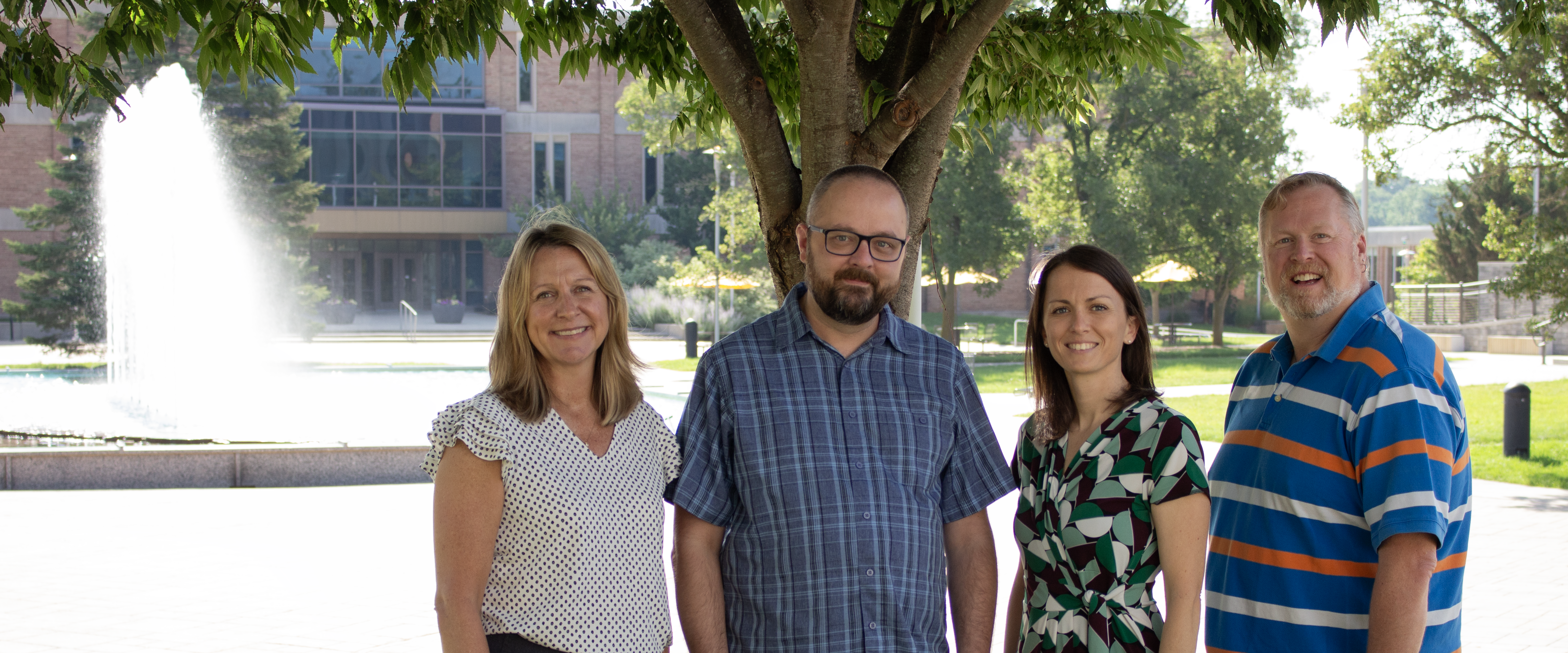 The College of Fine Arts advising team, AnneMarie, Nick, Destiny and Tom standing in front of the Campus Fountain.