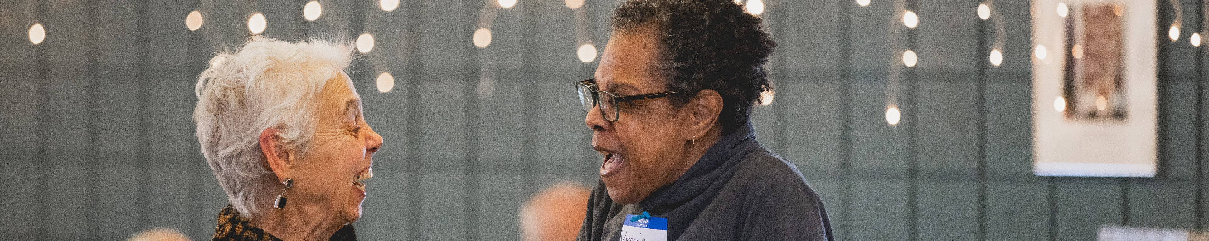 Two OLLI members laughing with each other at an event. 