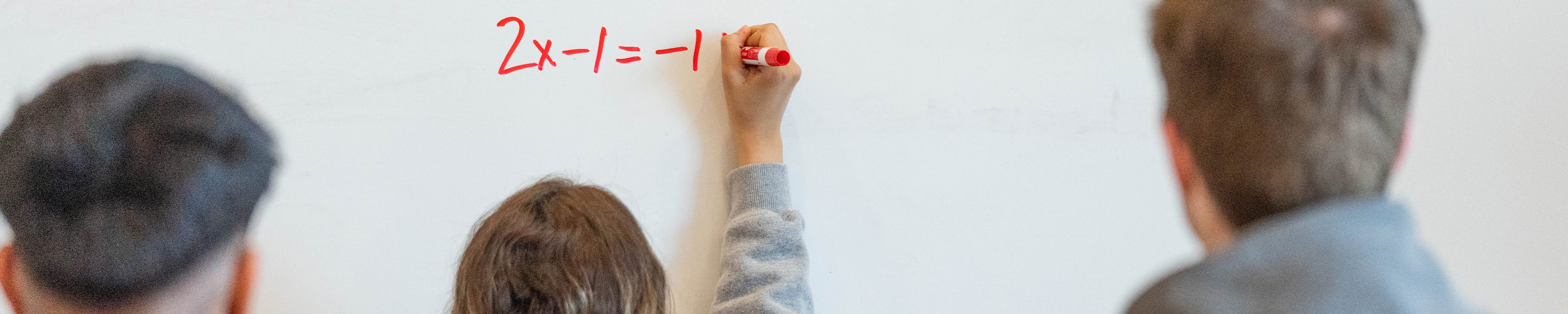 Three students solving for X on the whiteboard during a math tutor section.