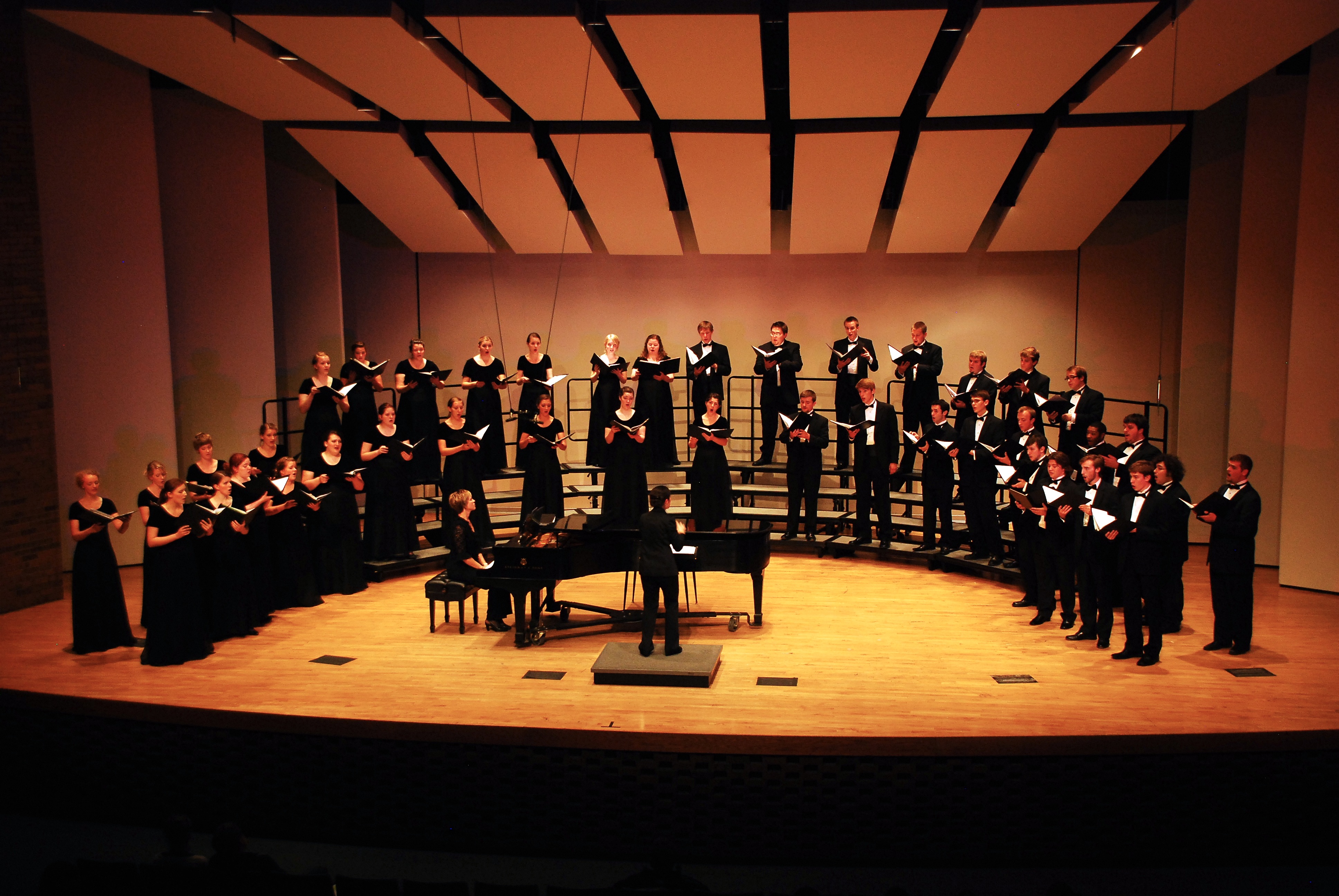 A choir performing on stage, accompanied by a pianist.