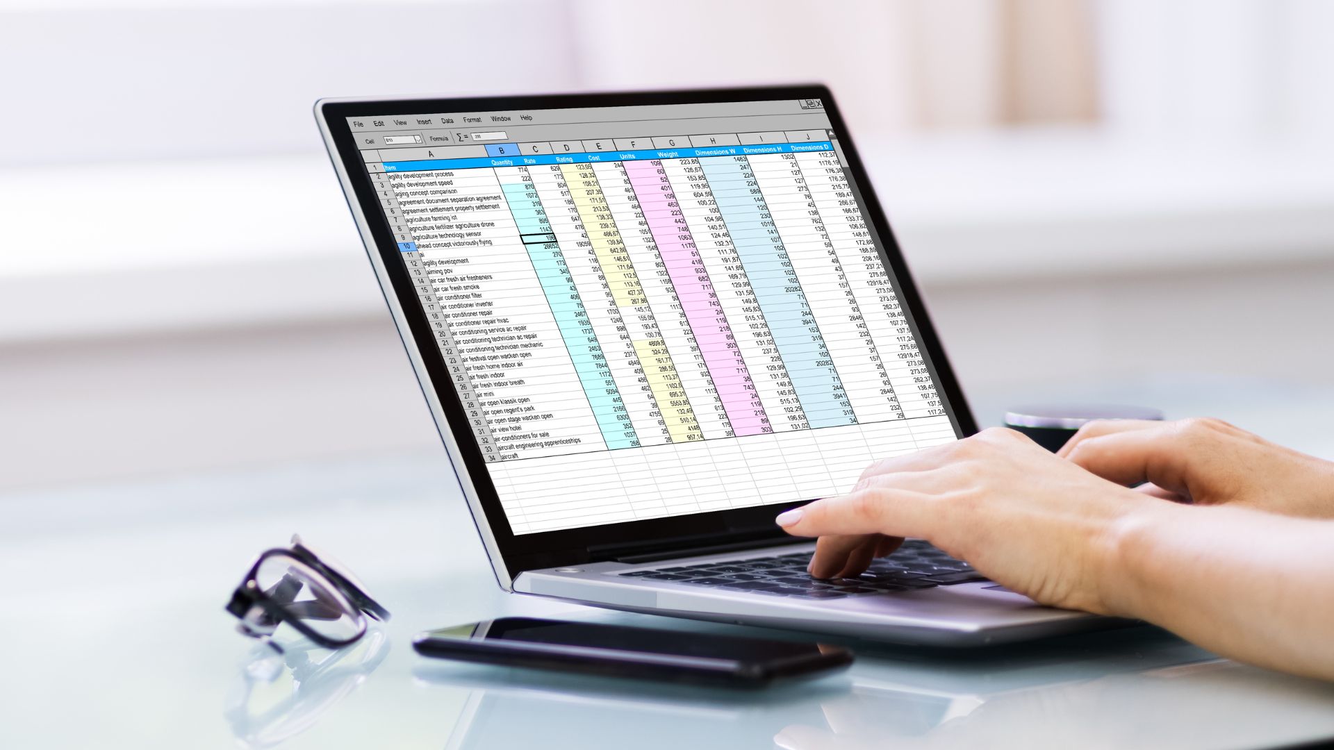 Hands on laptop entering data into a spreadsheet.
