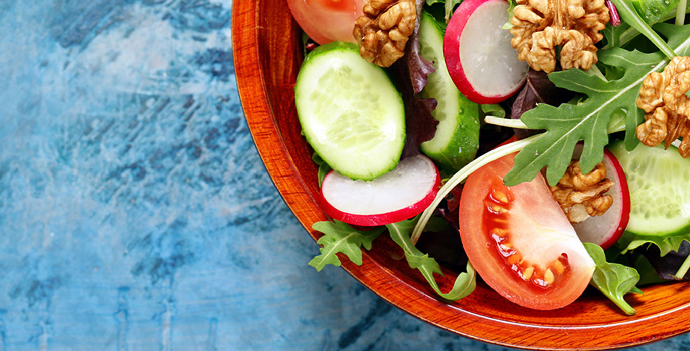 Vegetables on a plate with cucumbers and tomatoes with a blue background