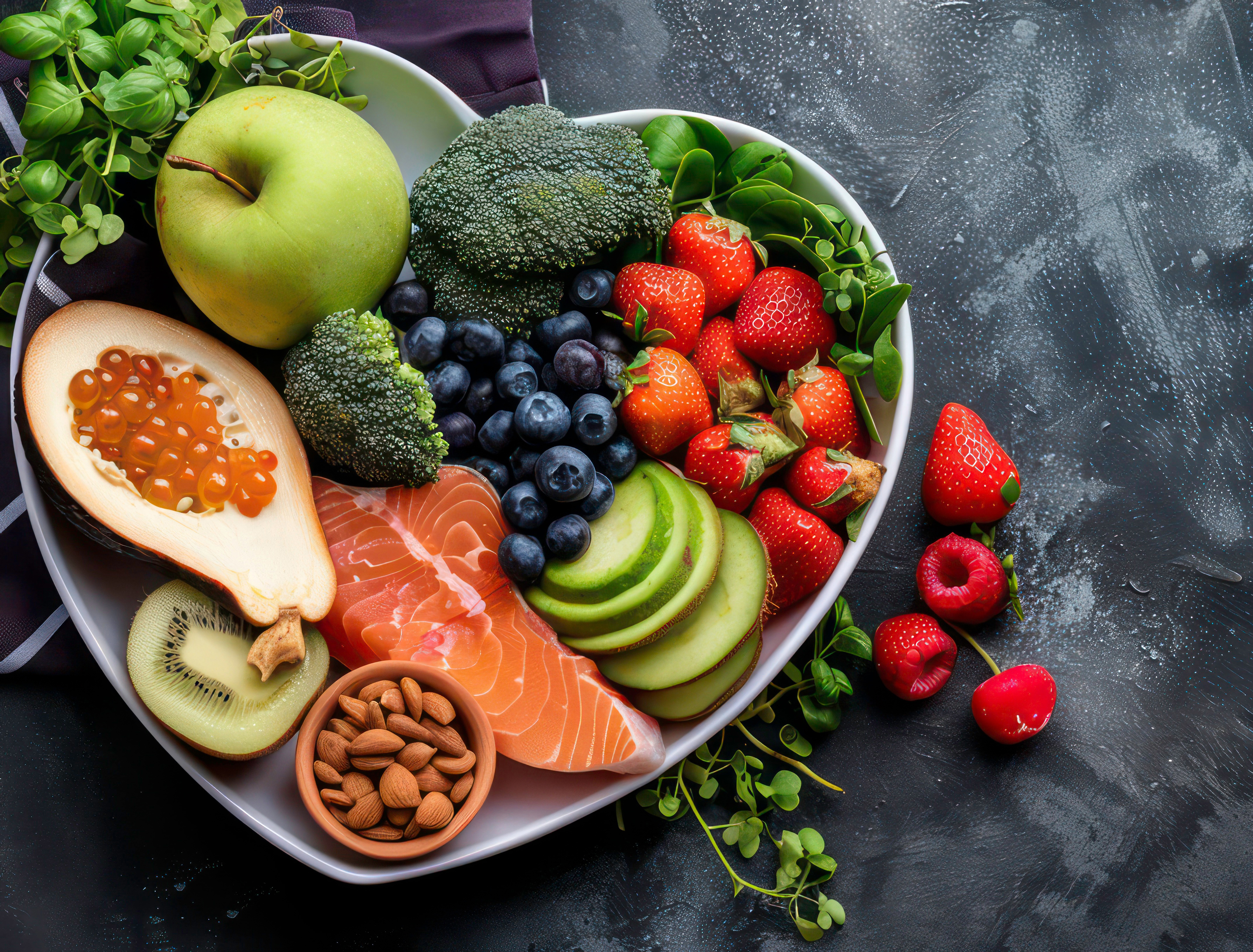 Platter with strawberries, green apple, avocado, fish, nuts, blueberries, broccoli, cucumber and greens 
