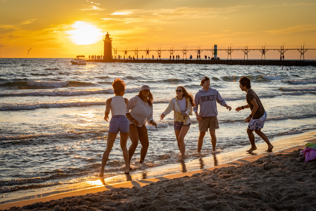 WMU students frolic at a beach during a sunset. 
