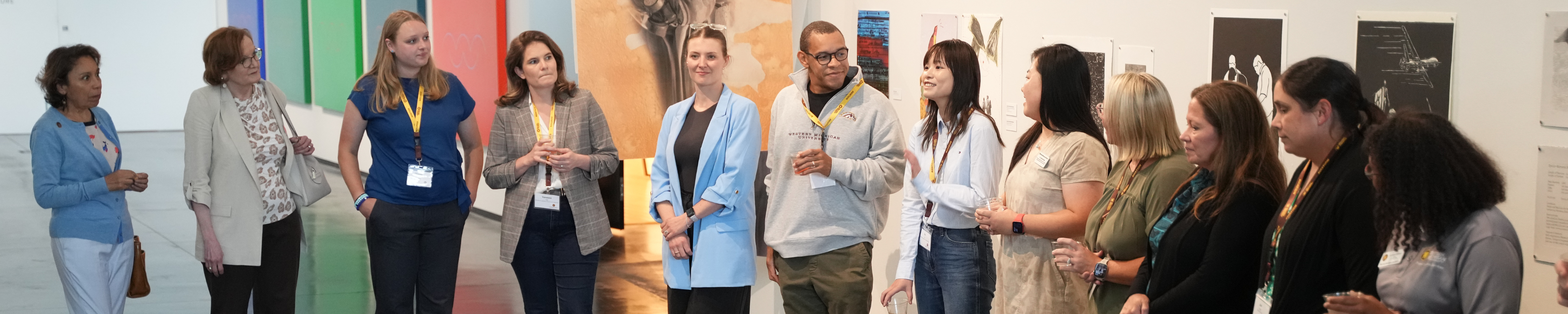 A group of new faculty and administrators standing in a circle for introductions during a new faculty orientation mixer at the Richmond Center for Visual Arts