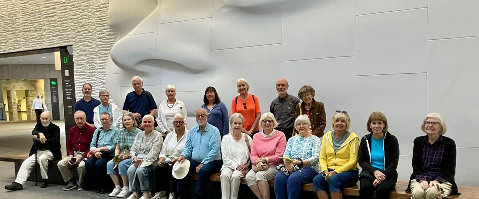 OLLI members posing in front of some art at the museum.