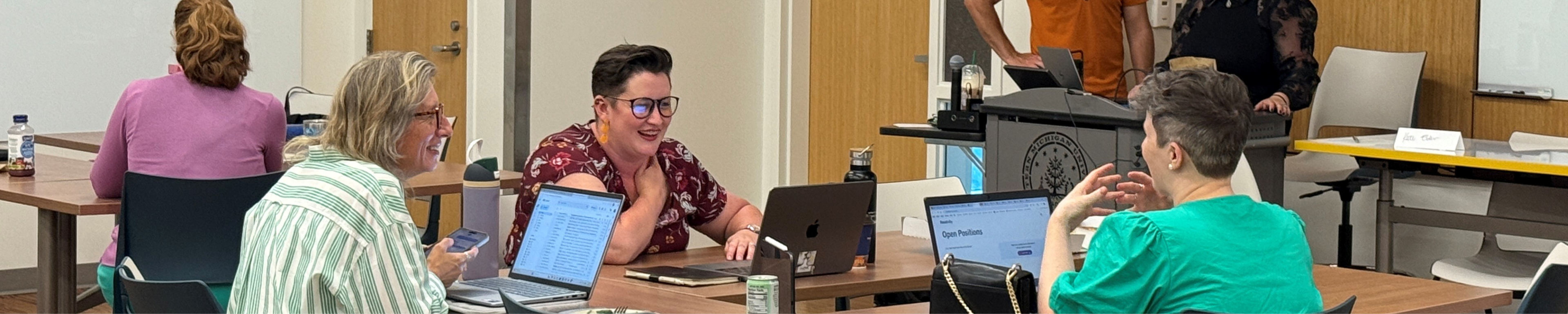 Three female instructors sitting at a table talking at Part-Time Instructor Orientation