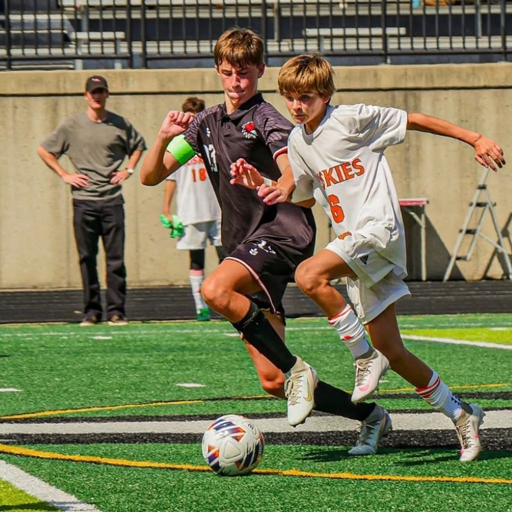 two soccer players going after the ball