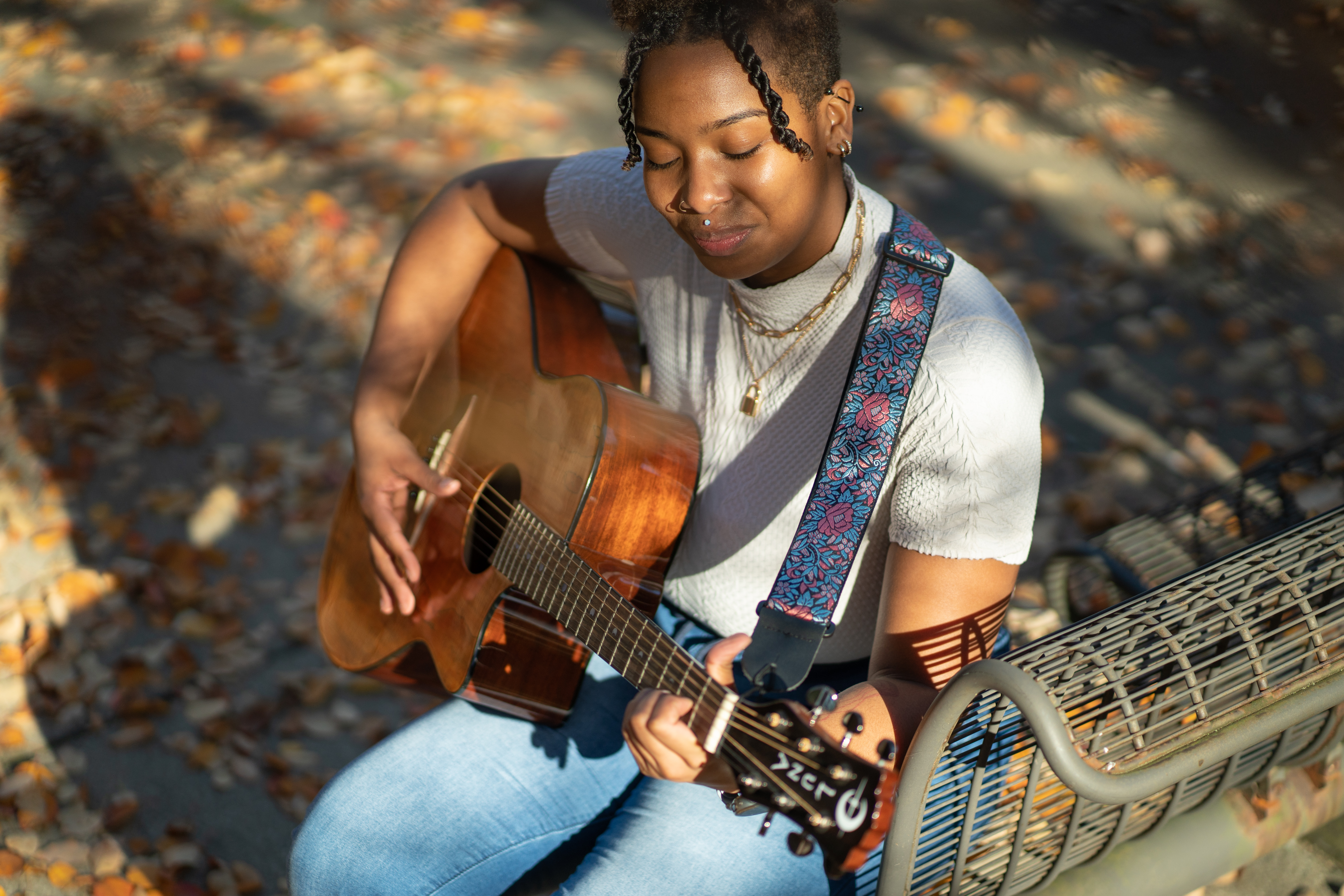 Music therapy student playing the guitar outside in the fall.