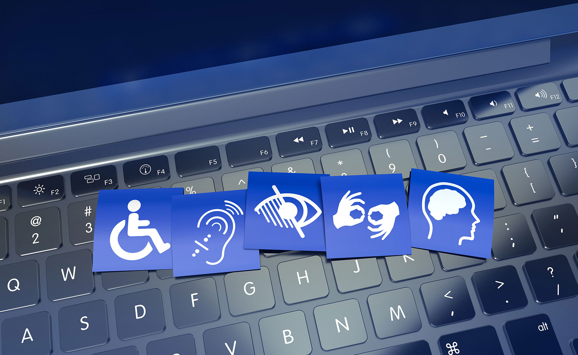 A computer keyboard with small printed sheets displaying accessibility icons, such as a wheelchair symbol and screen reader icon, placed on top.
