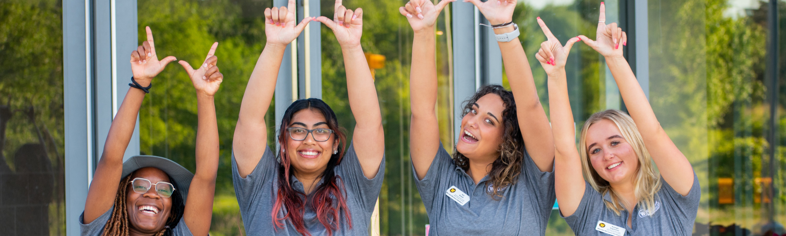 four women make a w with their hands in the air