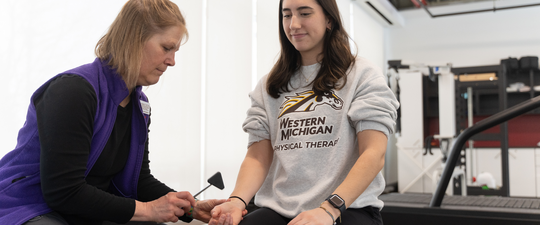 PT female faculty member demonstrates reflexes with a female student