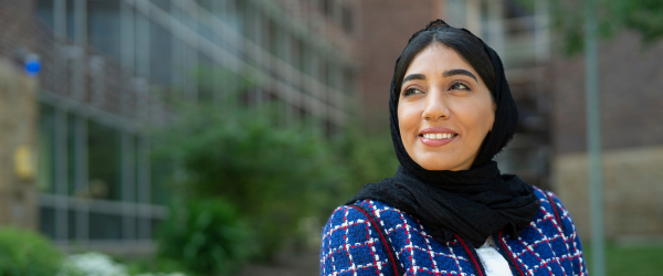 A female graduate student smiling in front of the college 