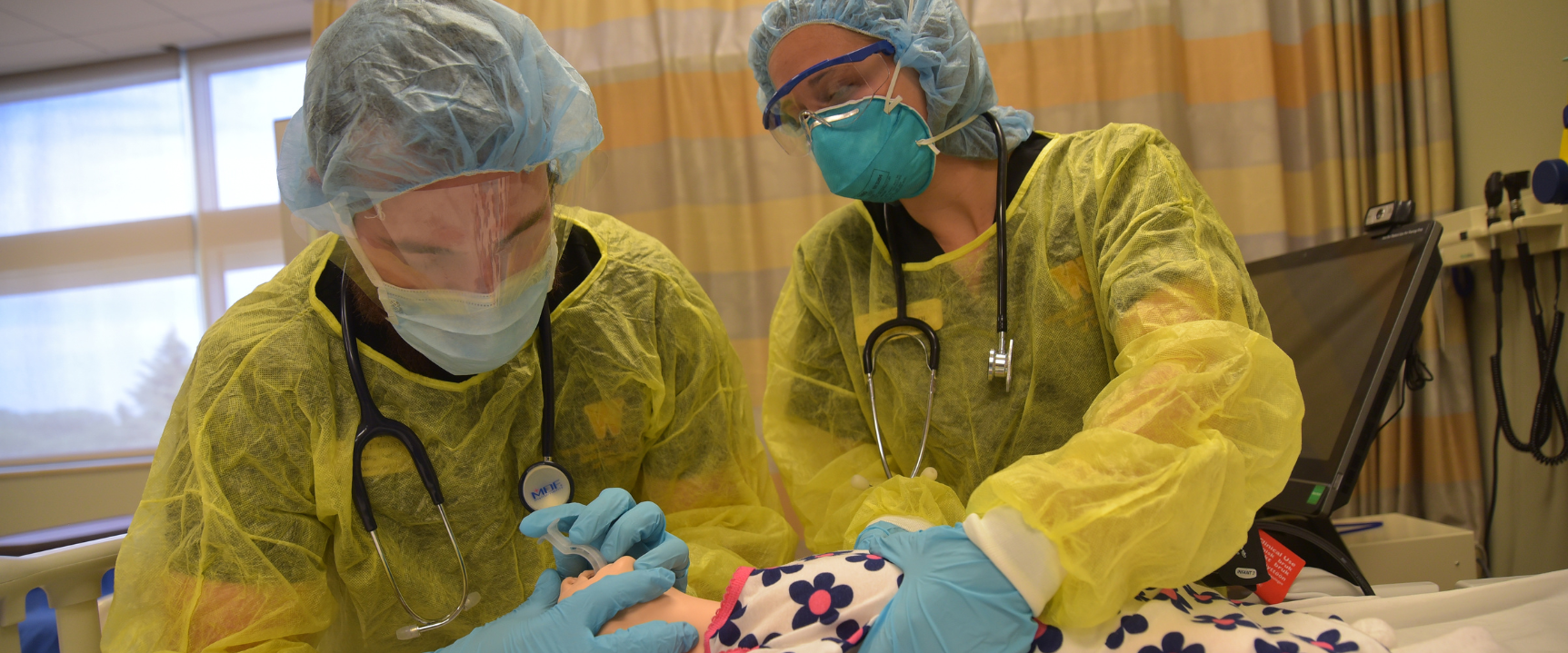 Two nursing students in PPE performing a simulation on a mannequin