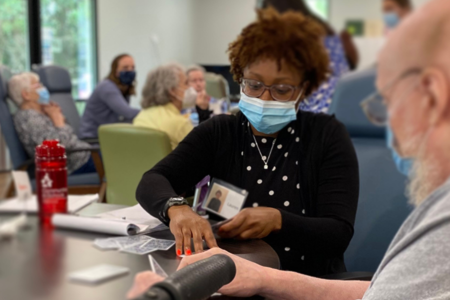 Female speech student with older man during speech therapy, playing a card game