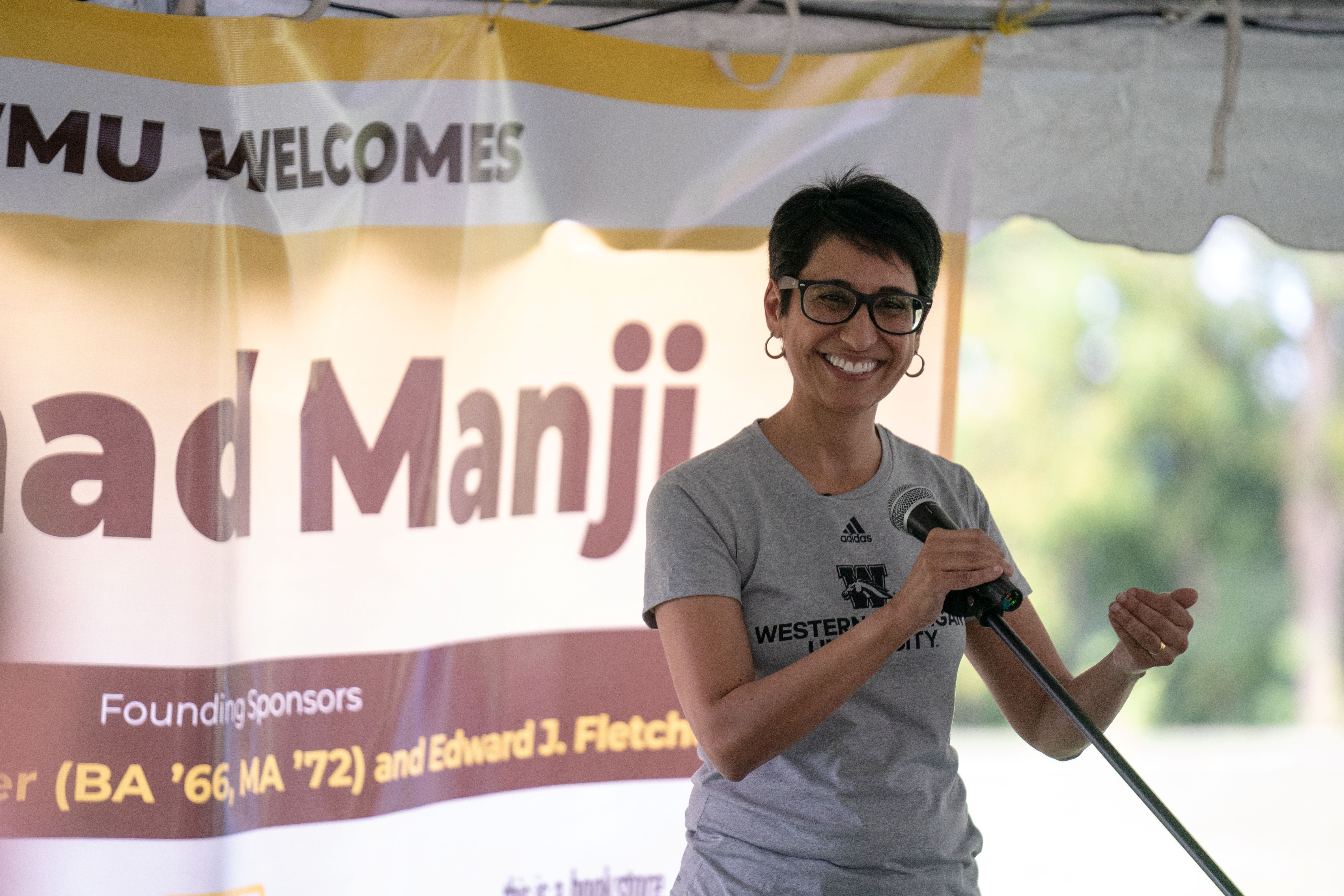 Irshad Manji posing in front of a banner while speaking at a WMU campus event