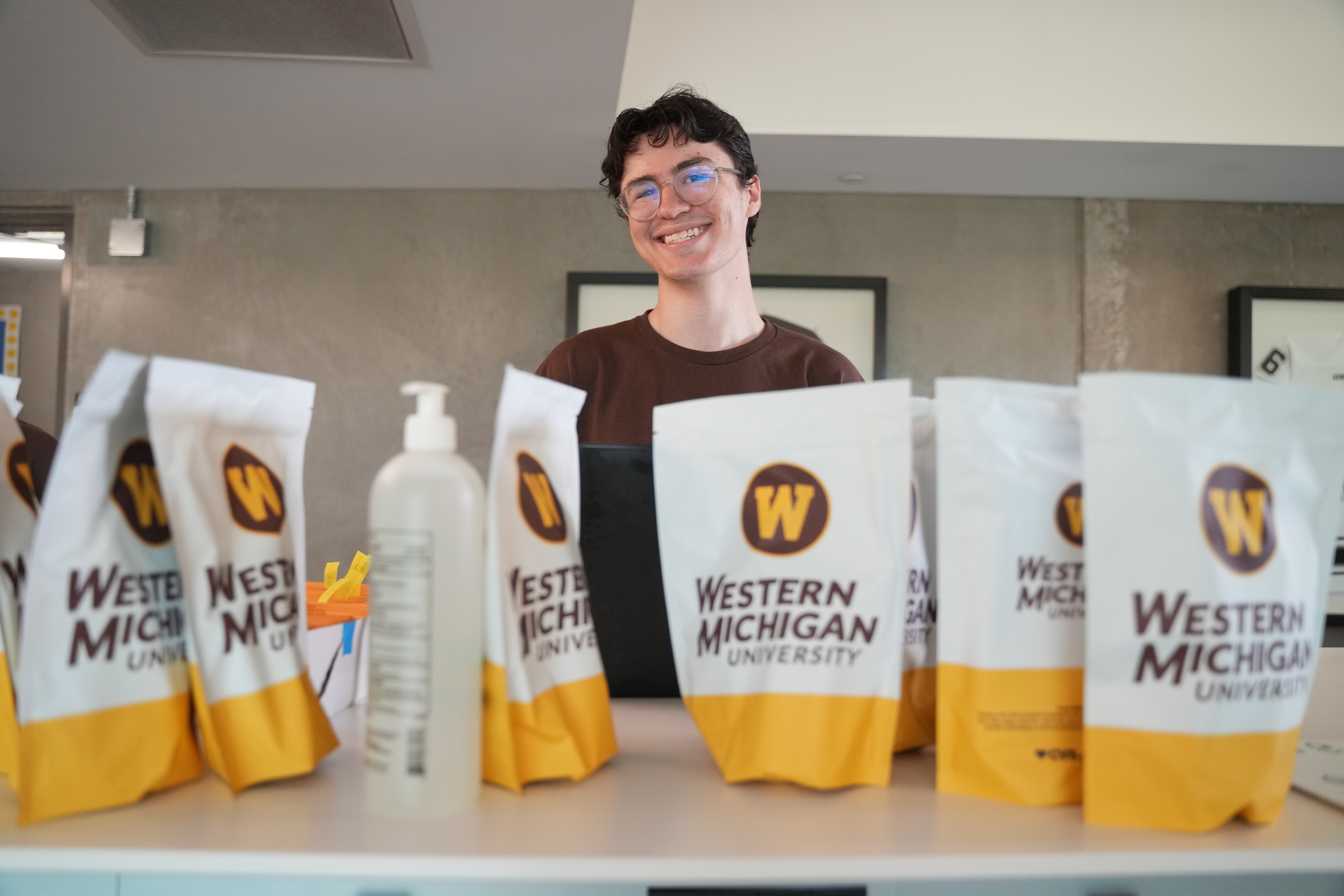 A student employee smiles at the check-in desk with WMU welcome bags.