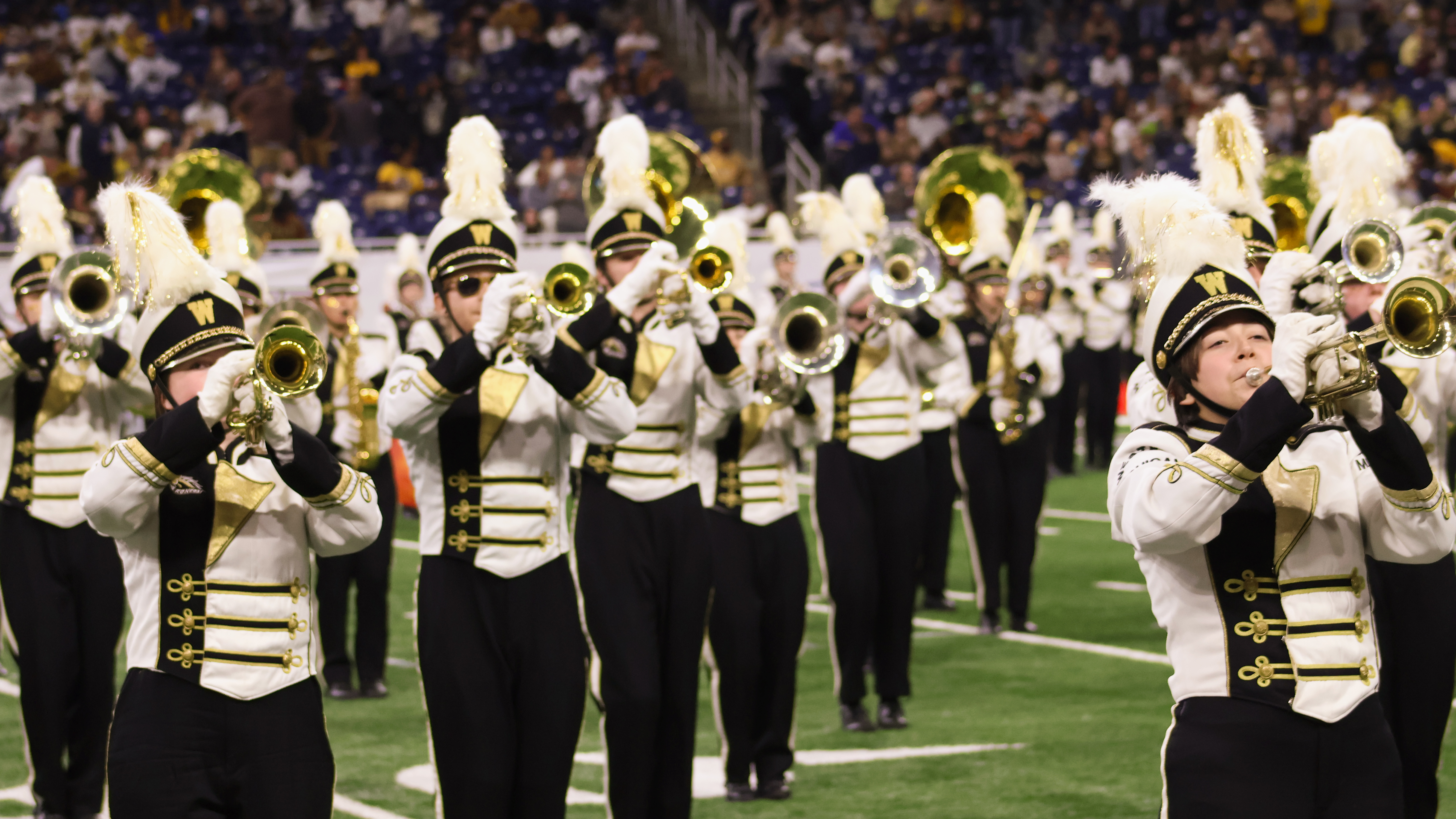 Bronco Marching Band members playing trumpets on the field.