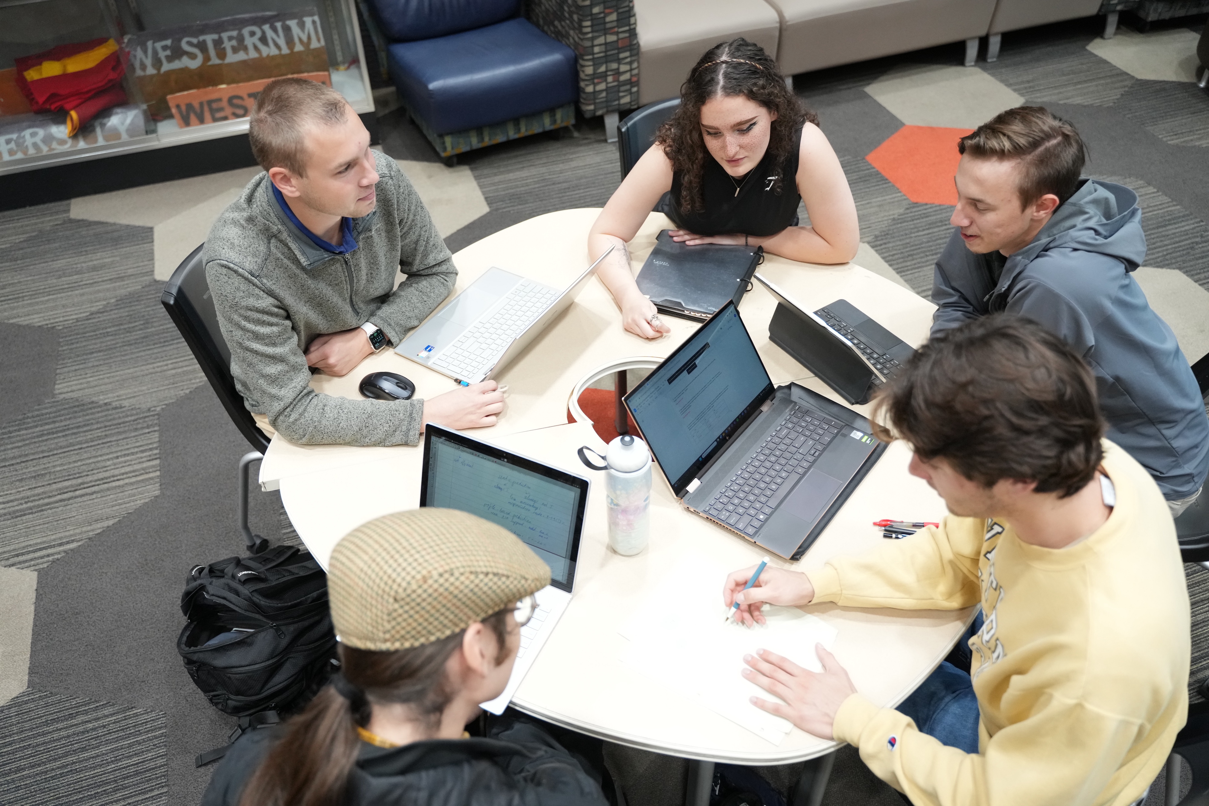 A group of College of Engineering and Applied Sciences students looking at computers during a meeting.
