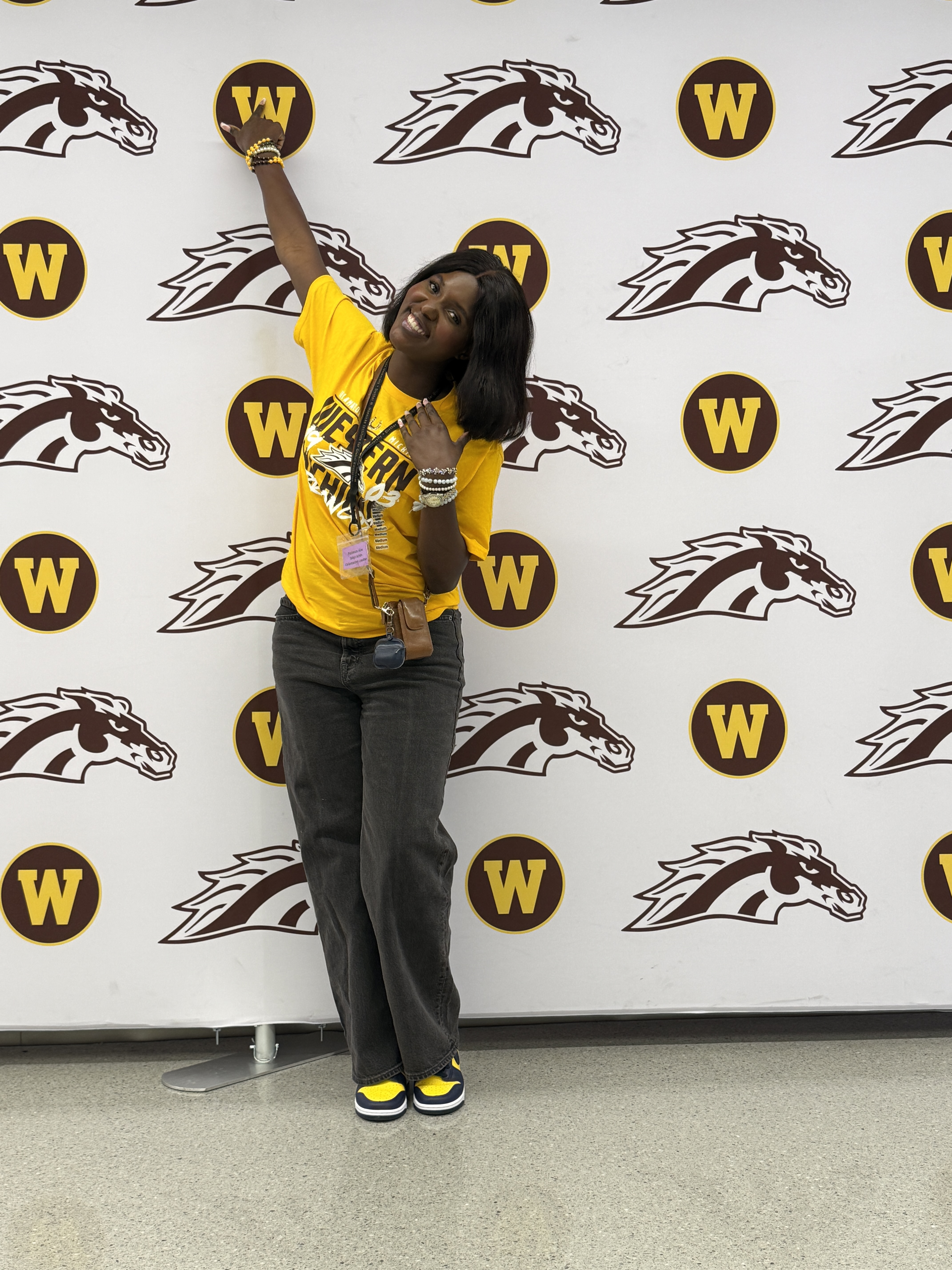 An international student poses near a Bronco backdrop on campus.