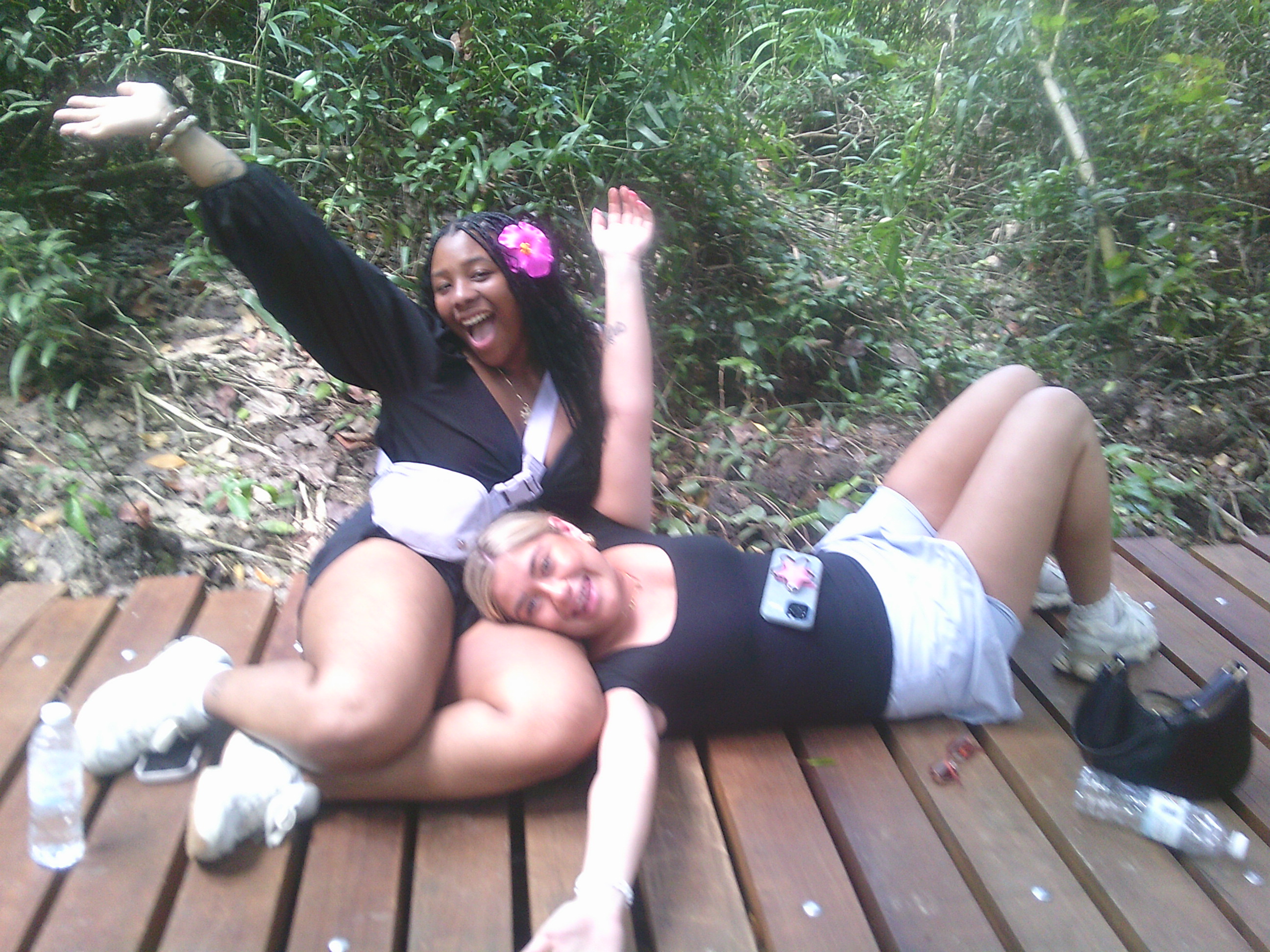 Two WMU study abroad students sit on a deck while raising their arms for a photo.
