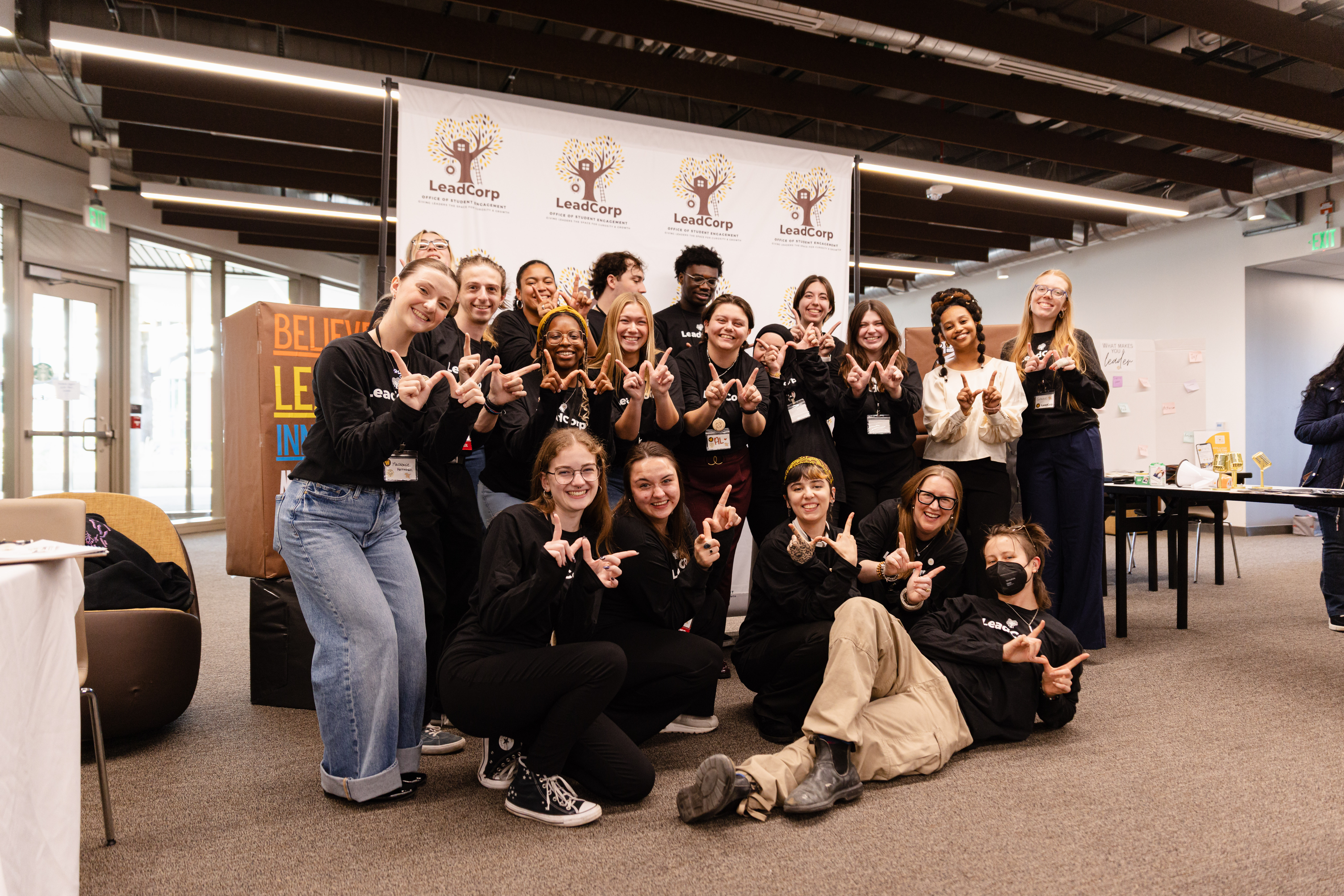Student leaders gather at a Western Michigan University leadership conference, posing together in front of a LeadCorp display while participating in leadership development and community building activities.