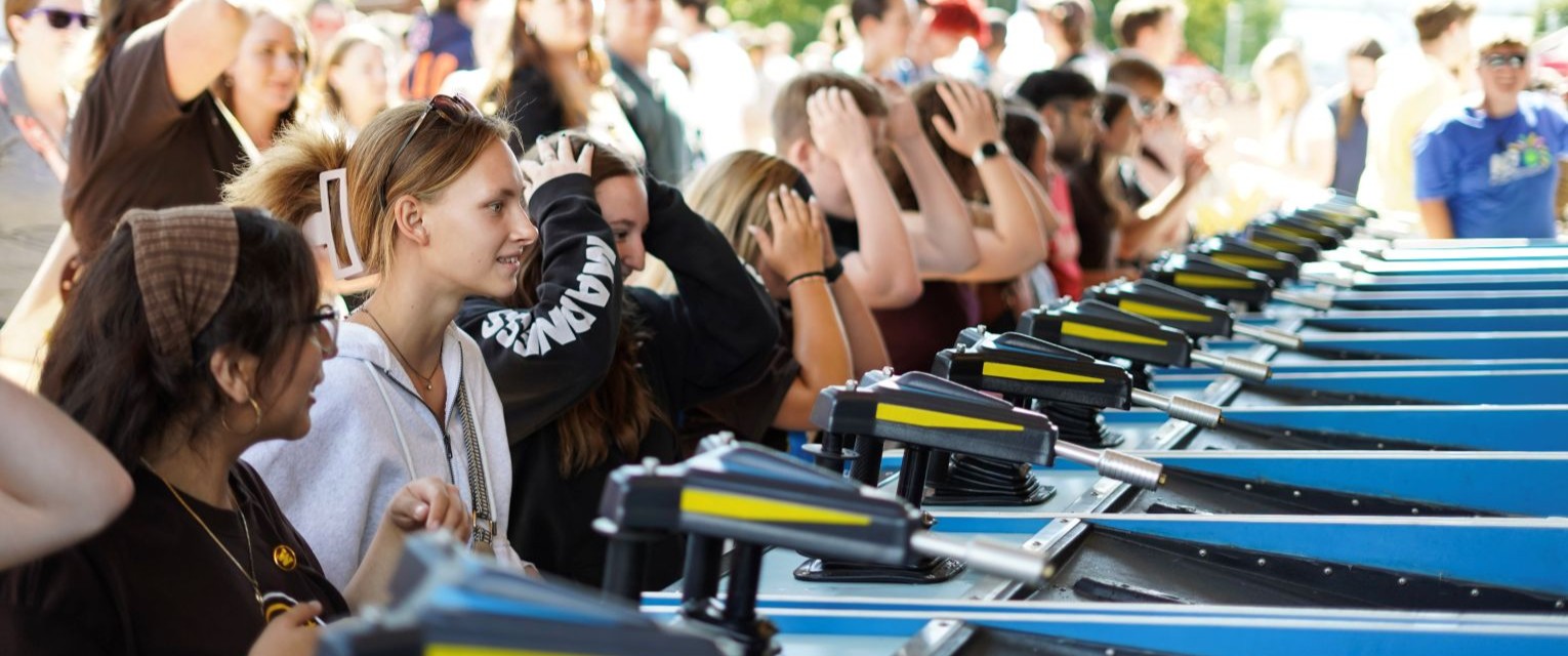 A large group of Western Michigan University students gathers and participates in a high energy game at Bronco Bash.