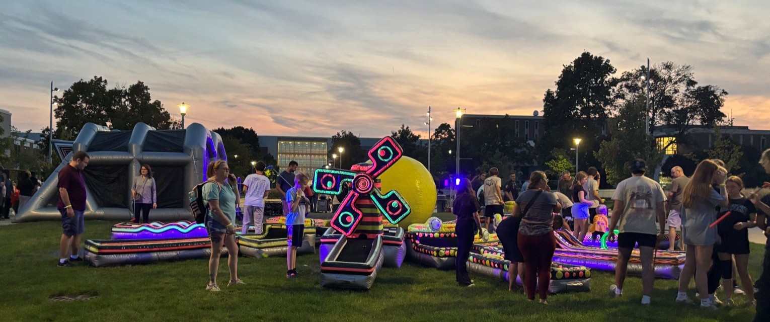 Students and families gather outside during a Western Michigan University Campus Activities Board event and participate in illuminated inflatable activities during Family Weekend..