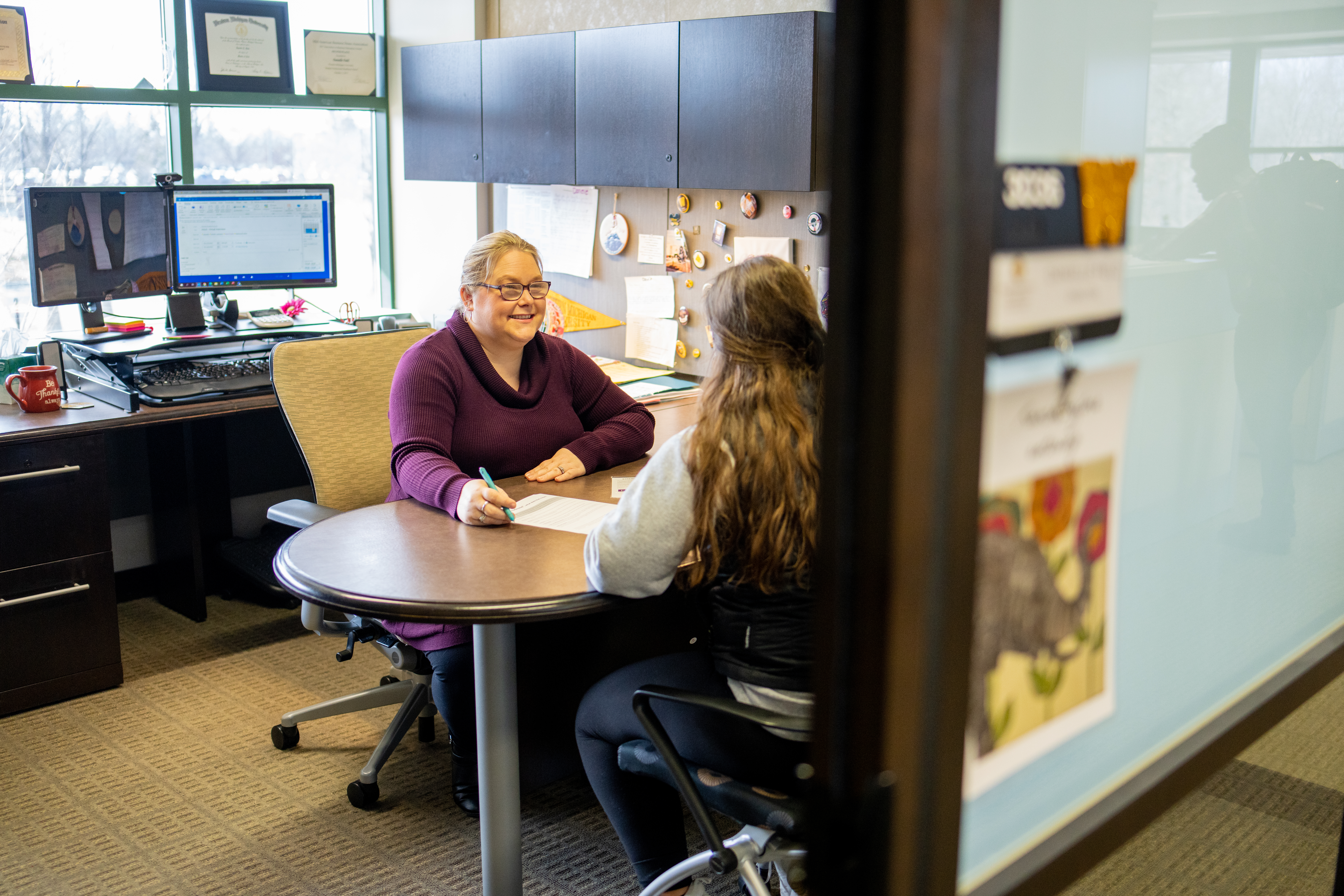 Student meets with advisor in an office.