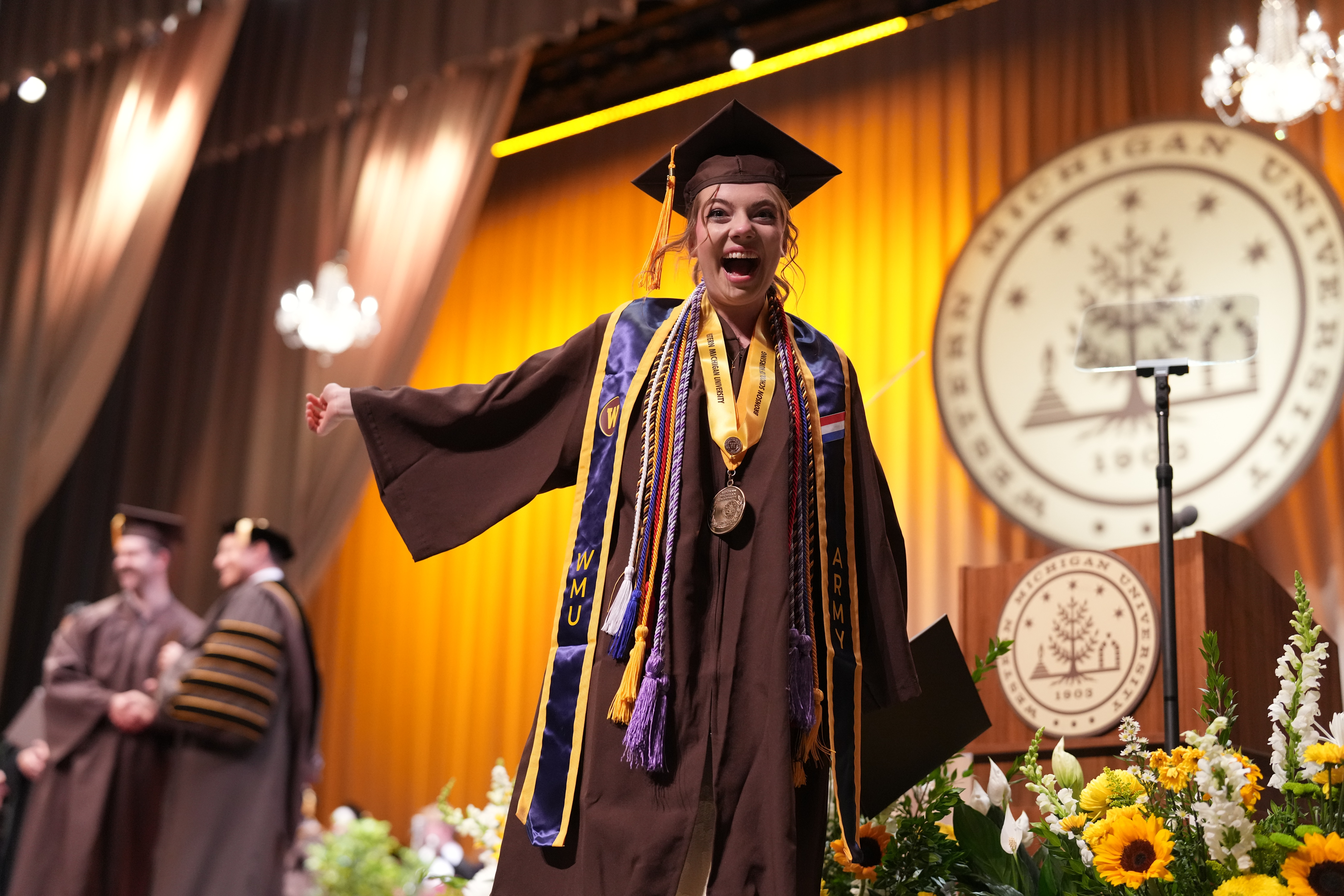 Honors grad Molly Cochran grins as she walks across the stage at commencement.