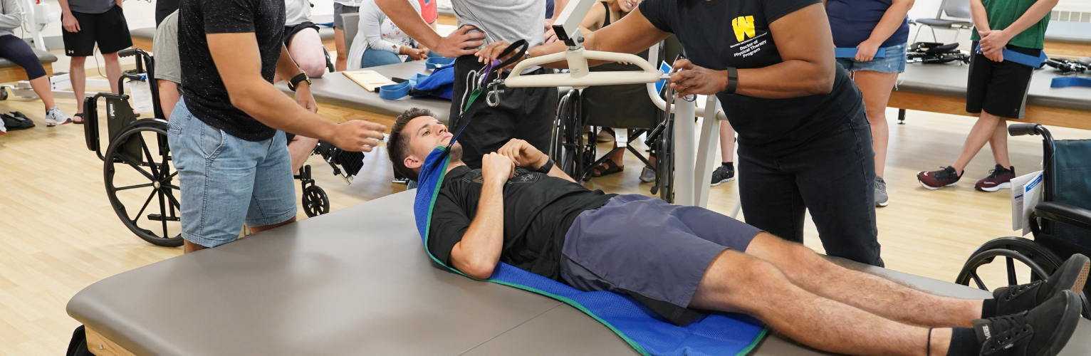students demonstrating transferring in a physical therapy classroom.