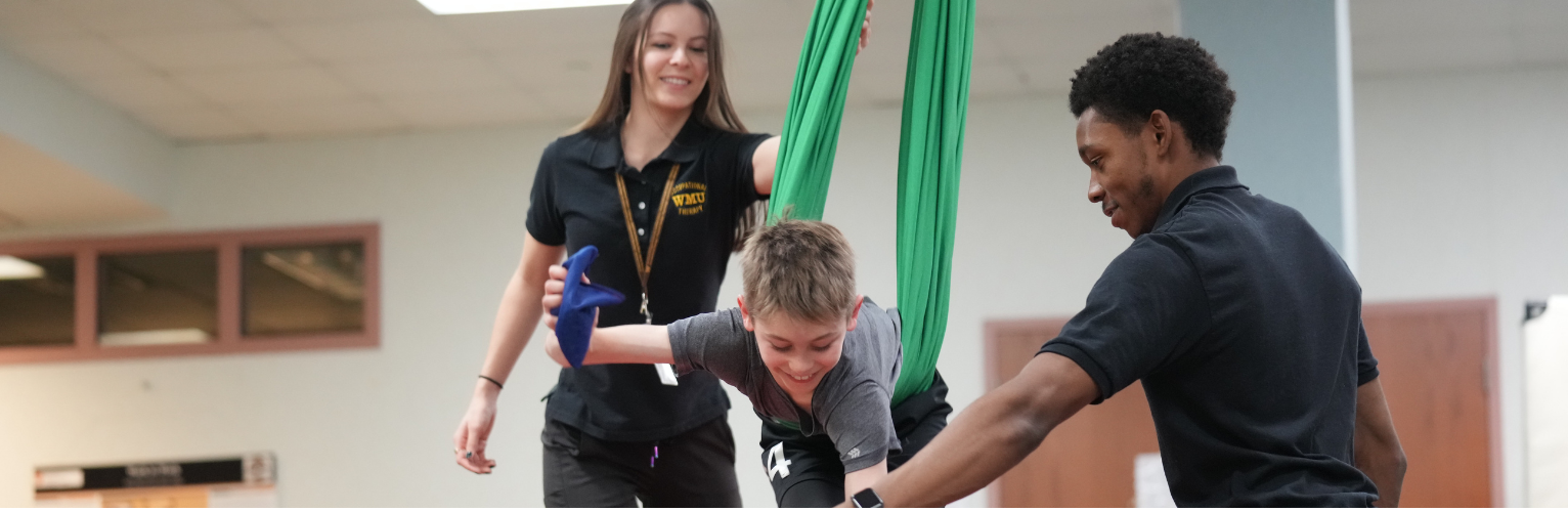 two occupational therapy clinicians working with a patient on a swing.