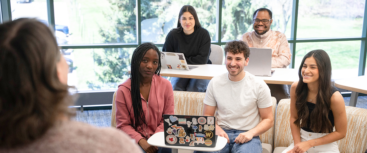 A group of students sitting together in front of their professor