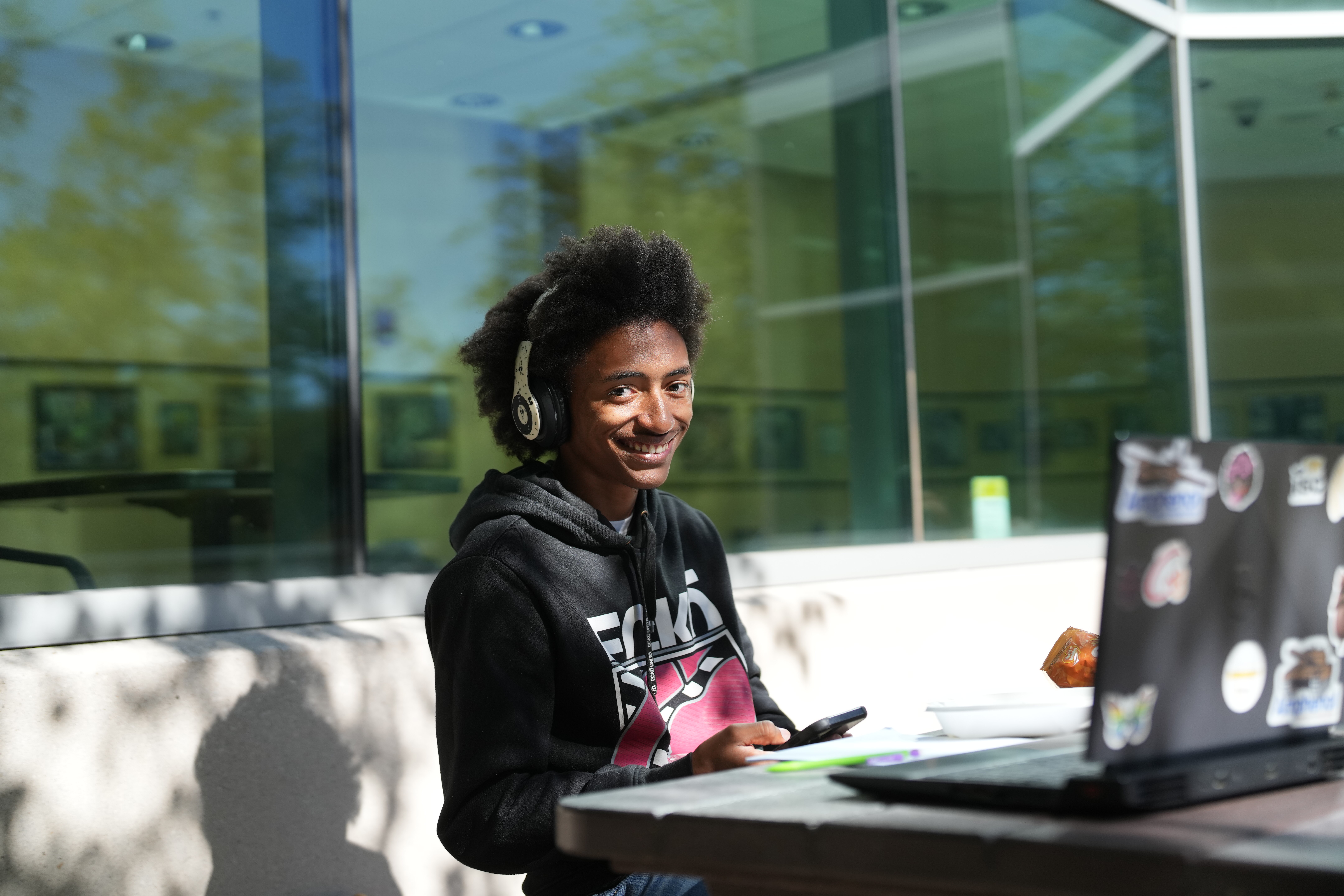 A student outside Floyd Hall sitting at a computer. 