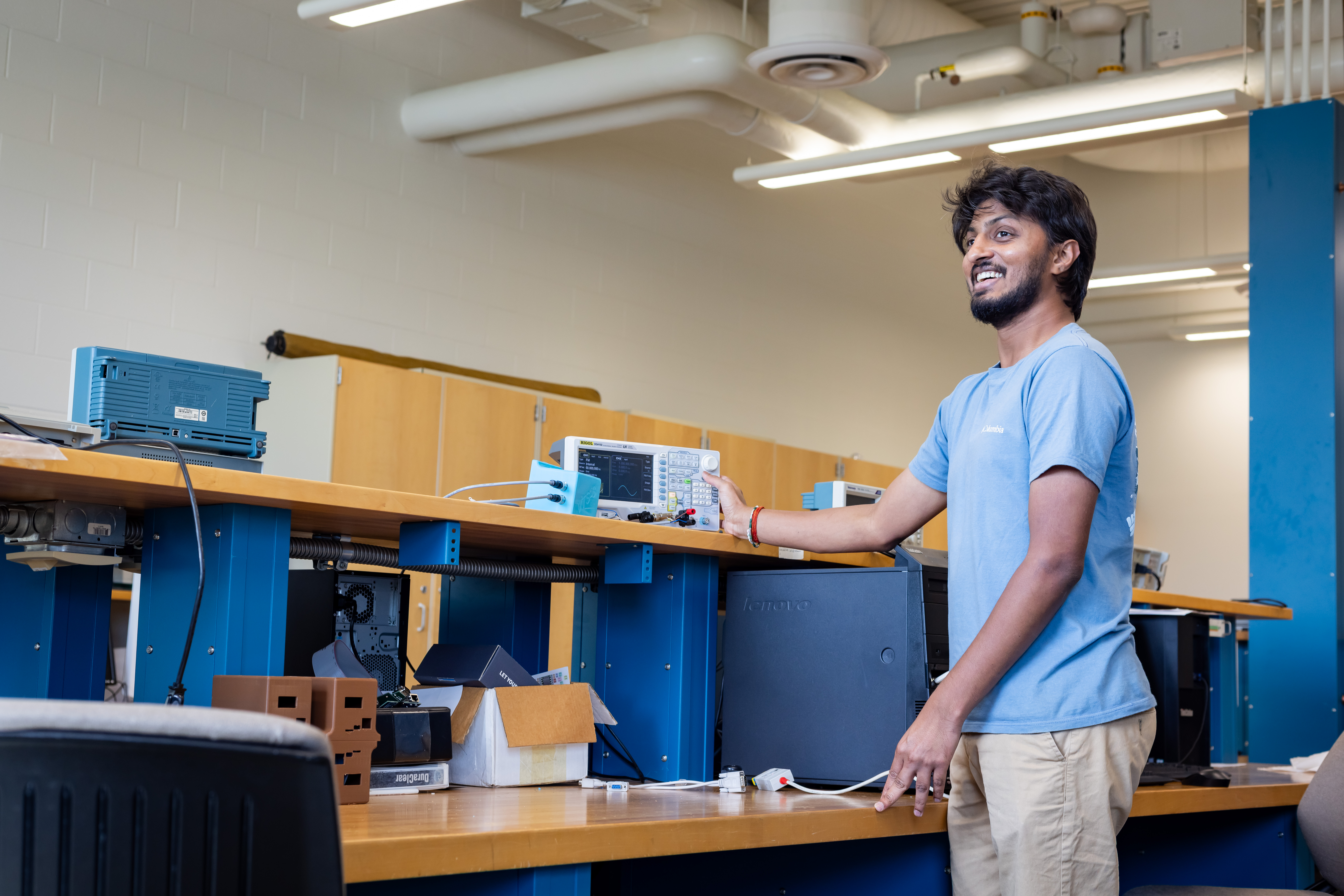 A student standing with a machine with circuits and wires. 