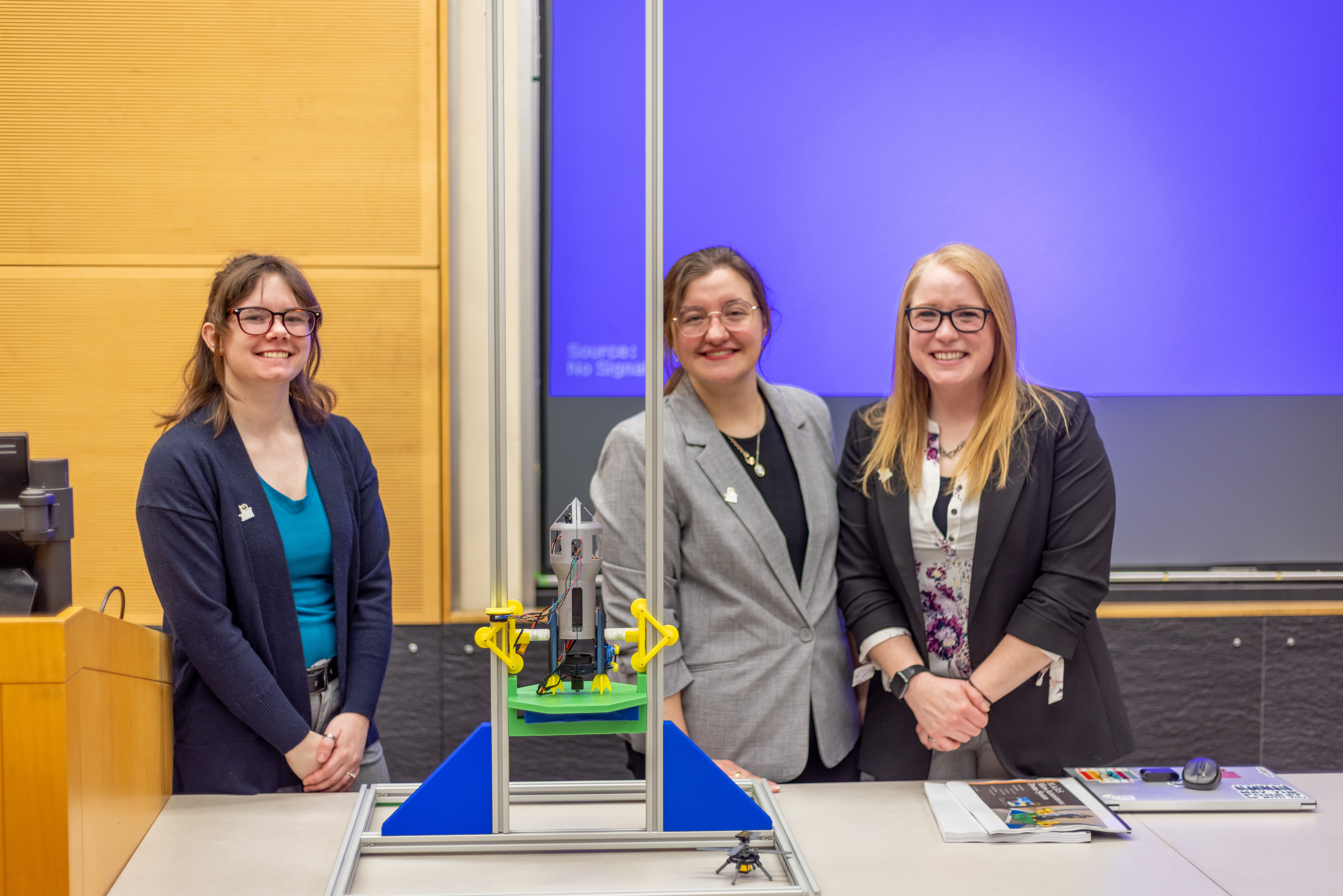 Three students presenting their capstone projects at the Senior Engineering Design Conference.