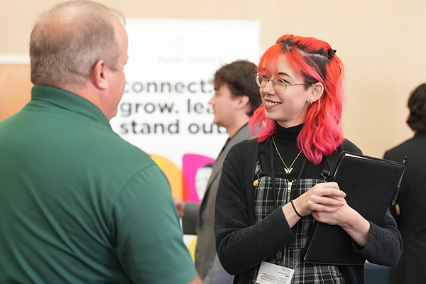 A student speaking with an employer on campus