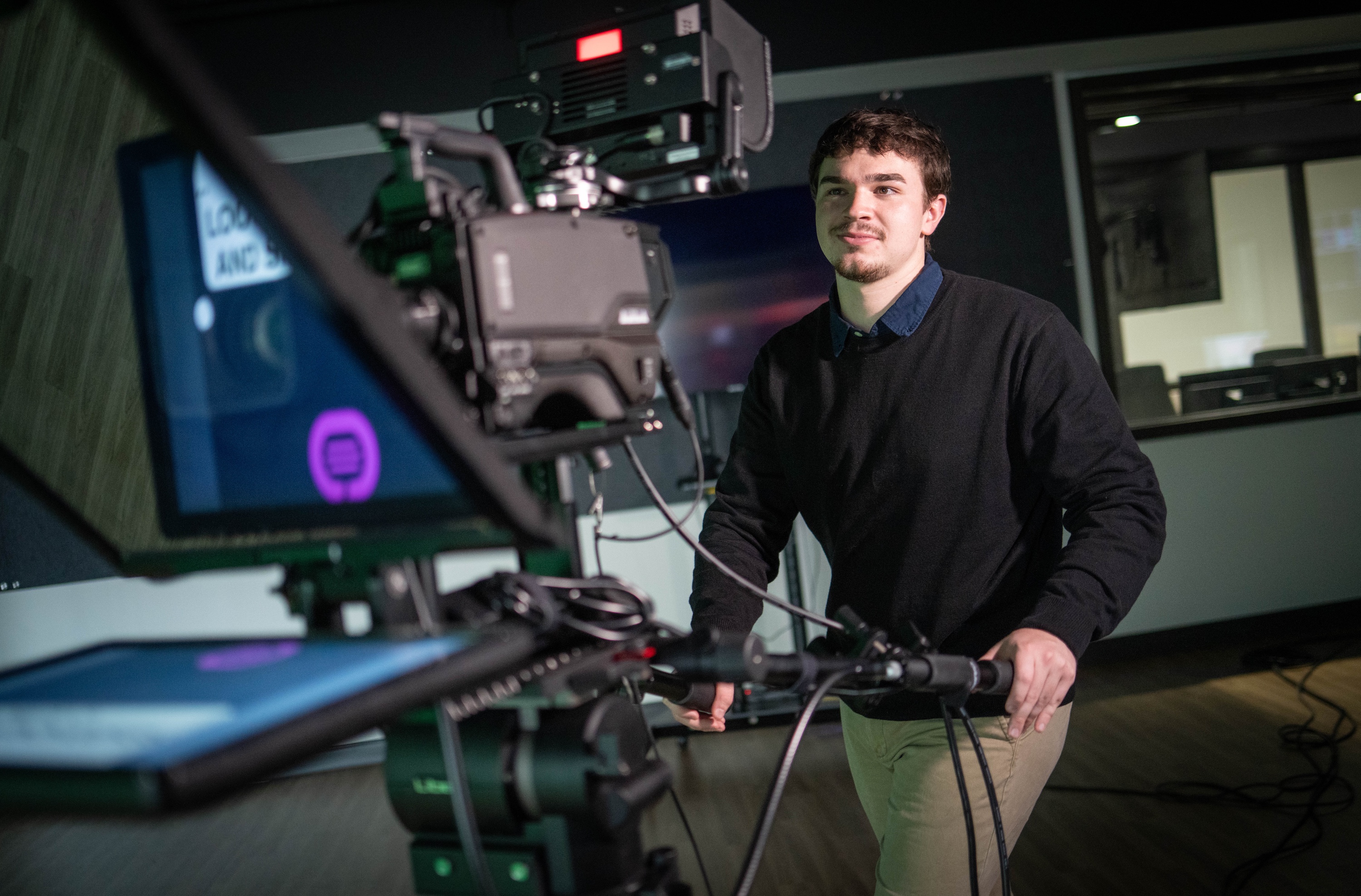 Aidan Ralko working with a professional grade video camera in a studio.