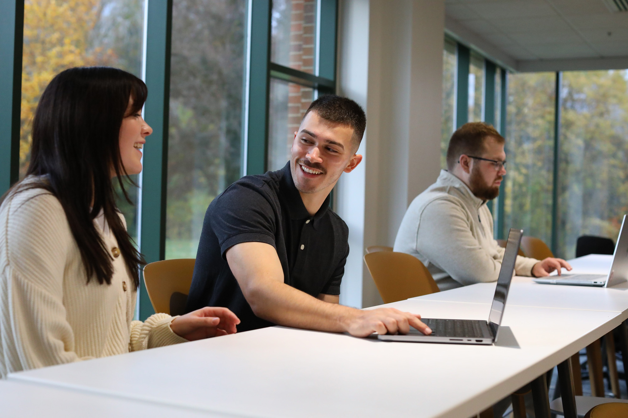 Three grad students seated at a table interacting