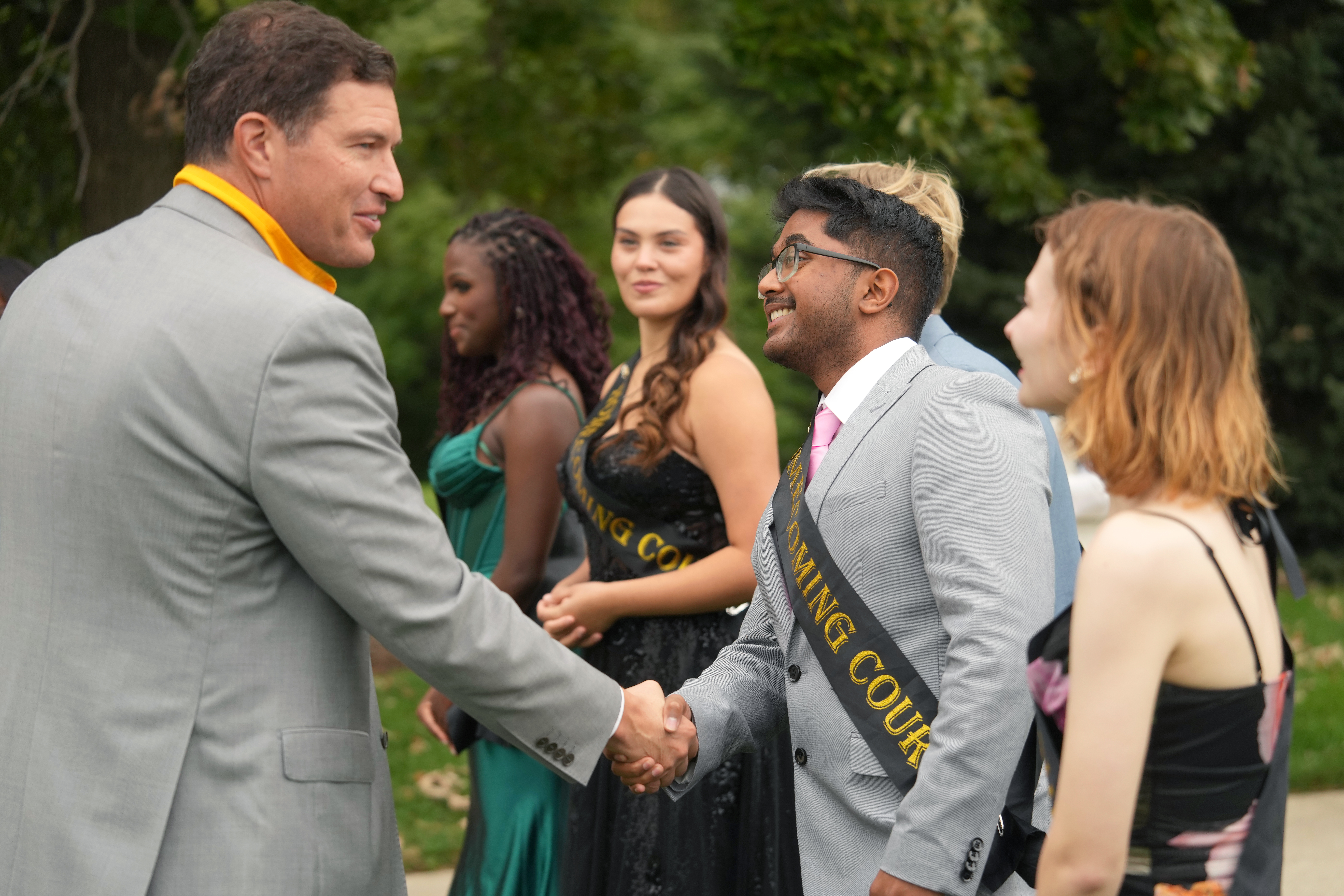 WMU President shaking the hands of homecoming court members