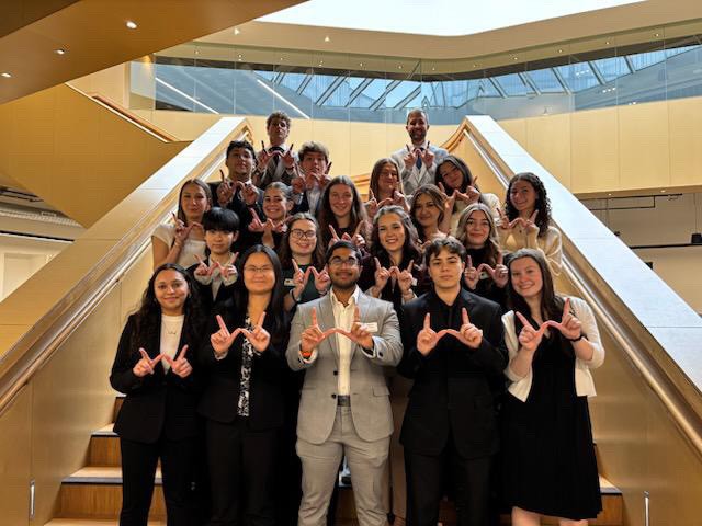 The Peer Student Success Team mentors stand on a staircase, making the W with their hands.