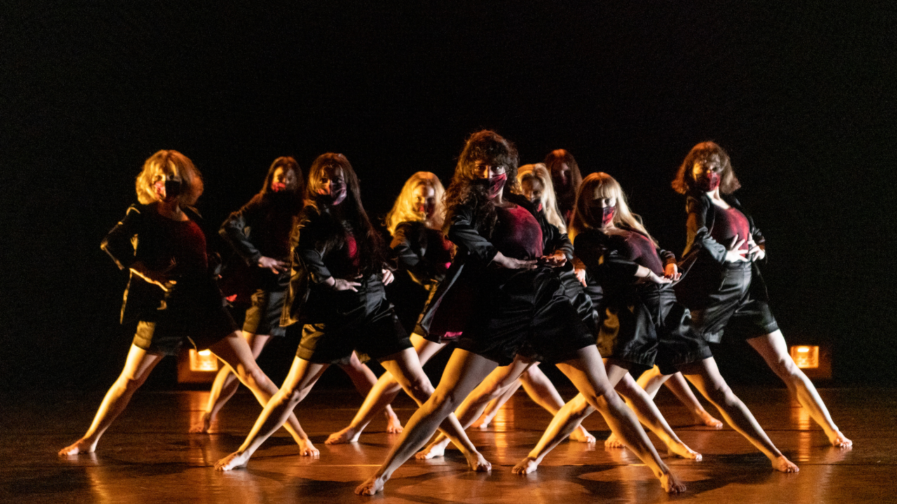 a group of woman wearing masks in a unison dance pose.