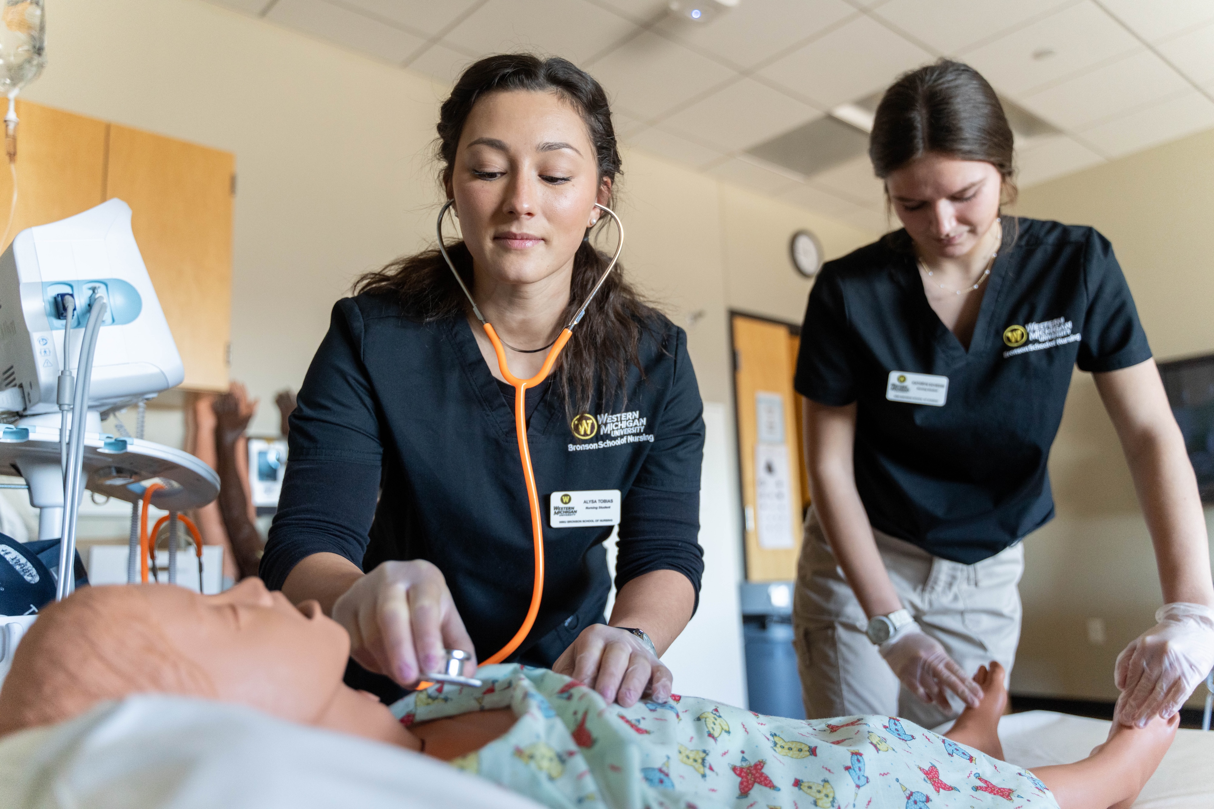 Bronson School of Nursing students practicing hearing the lungs and checking the feet of a patient dummy.