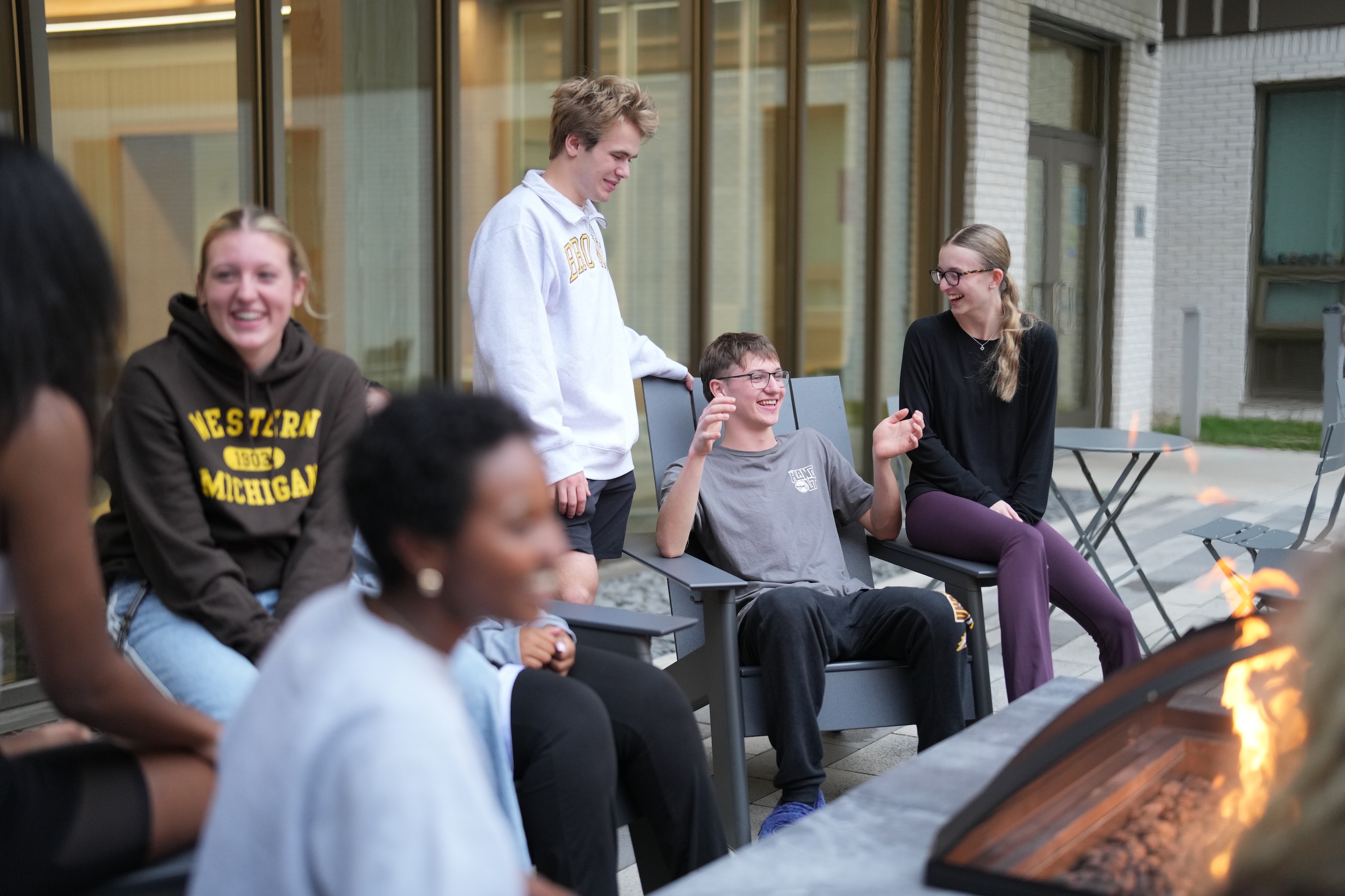 Students laughing and talking around the fire pit at Valley Oaks Residence Hall.