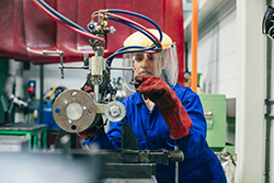 An female engineer works on a machine in an engineering workshop.