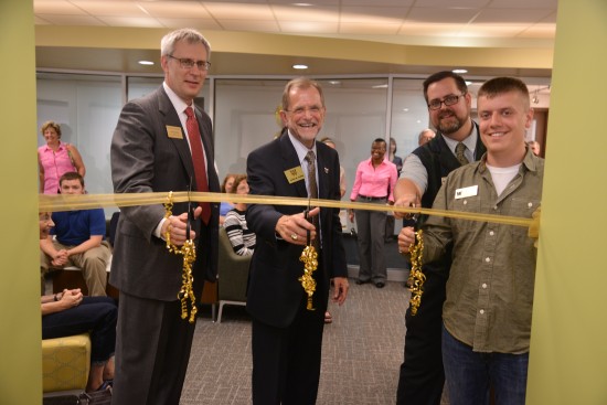 Four people cutting grand opening ribbon