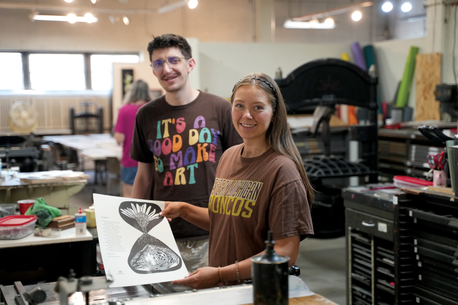 Grant Overbeek and Maddy Boguslawski hold a page of a book near a press.