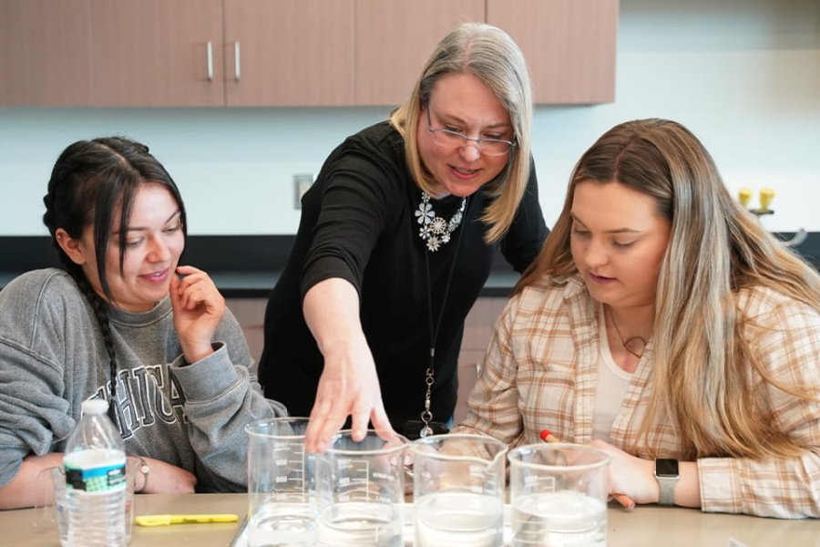 Teacher instructing students during a chemistry exercise. 