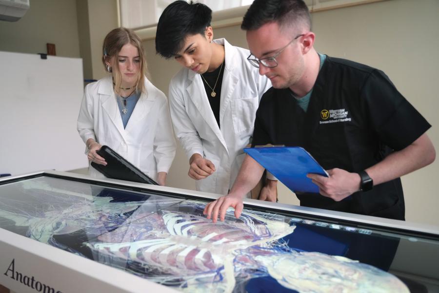 Two students and an instructor working on the anatomage table.